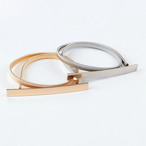 Close-up detail of gold and silver elastic metal belts with polished rectangular buckles
