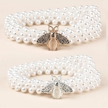 Detail of multi-layer pearl belts featuring gold and silver rhinestone bee buckles