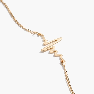 Chaîne de corps minimaliste avec pendentif EKG en métal doré poli sur fond blanc