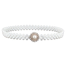 Detail of double-layer pearl belt featuring a rhinestone flower buckle on white background