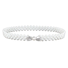 Detailed macro view of triple-row pearl waist belt with rhinestone-encrusted bow buckle