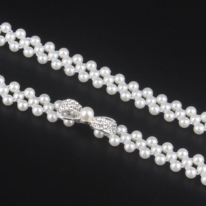 Macro shot of double-row pearl belt featuring a rhinestone-encrusted bow clasp