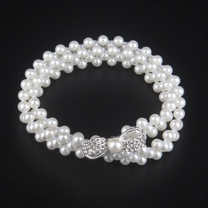 Detail of multi-layer white faux pearl bracelet featuring a sparkling rhinestone bow clasp