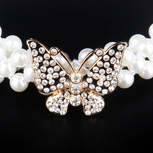 Close-up of sparkling rhinestone bow buckle with elegant white faux pearl strands