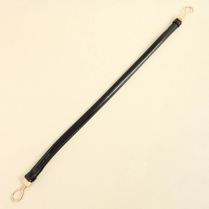 Detail of black faux leather strap with gold teardrop metal clasps for handbags