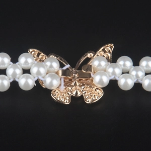 Detailed macro view of double-layer pearl belt with golden butterfly metal buckle