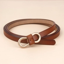 Detail of slim dark brown leather belt for women with oval silver metal buckle