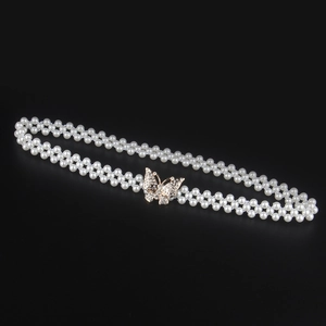Detail of elegant pearl waist belt featuring a rhinestone-encrusted golden bow buckle
