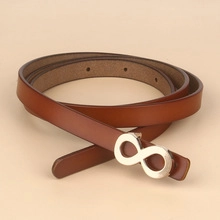 Detail of the golden infinity buckle on a premium dark brown leather fashion belt for women