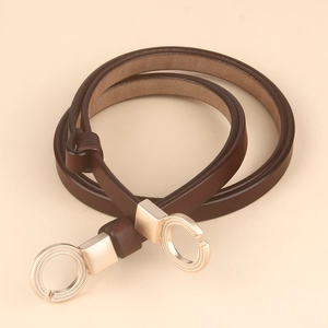 Detail view of thin brown leather belt with gold double-ring buckle and woven texture