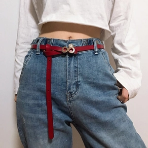 Fashionable red leather waist belt with silver infinity buckle on blue denim jeans