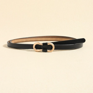 Detailed close-up of slim black leather belt with elegant matte gold bow-shaped buckle