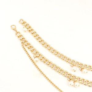 Close-up of golden multi-layer metal waist chain featuring white pearls and lobster clasp