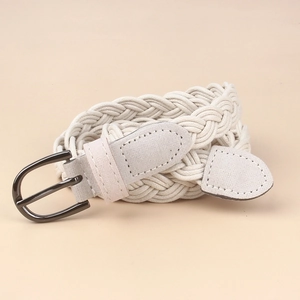 Detail shot of a cream woven elastic belt with a dark metal pin buckle and matte finish cap