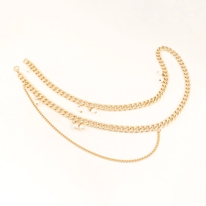 Close-up of layered gold metal waist chain featuring elegant white pearl charms