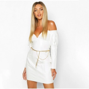 Detailed view of multilayer gold chain belt with pearls on a white off-shoulder dress