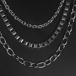Detail of three-layer punk hip-hop silver metal chains with mirror finish on black background