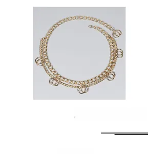 Detail of double-layer gold metal body chain with circular pendants and lobster clasp