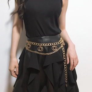 Detail of layered gold metal body chain featuring dual rings and long tassel pendants