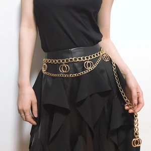 Detailed view of layered gold geometric body chain with double ring charms on a black dress