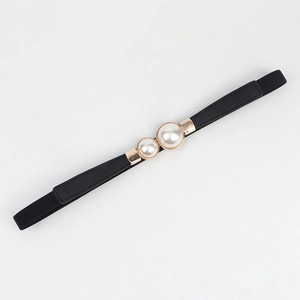 Détail de la fine ceinture noire élastique avec une élégante boucle à double perles dorées