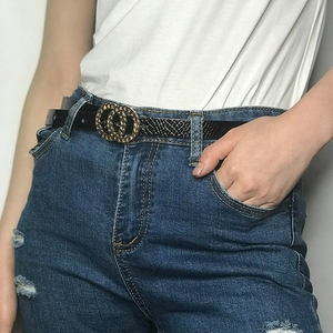 Detail of black faux snake leather belt with golden double O buckle on blue denim jeans