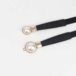 Détail d'une fine ceinture élastique noire avec boucle dorée et perles blanches