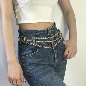 Detail of a multi-layer gold waist chain with rhinestones on blue denim jeans