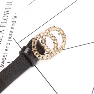 Close-up of black embossed faux leather belt with a textured golden double ring buckle