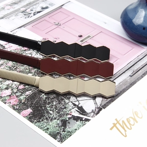 Detail of three elastic belts with geometric buckle in black, dark red, and cream white
