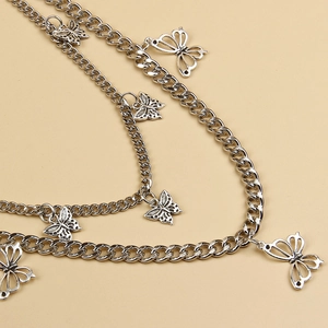 Detail of silver layered chain with intricate butterfly pendants on a neutral surface