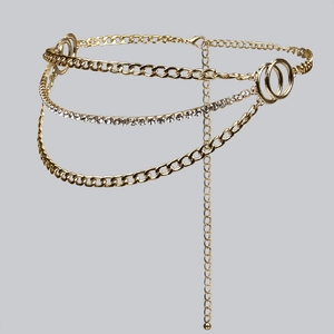 Detail of multi-layer golden waist chain featuring Cuban links and clear sparkling rhinestones