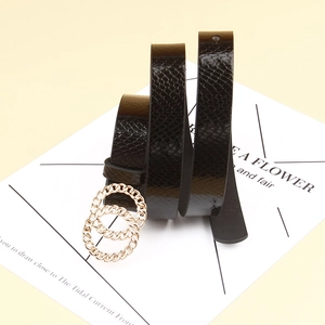 Detail of black faux leather belt featuring snake texture and gold double O-ring buckle