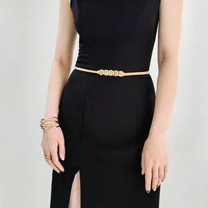 Close-up of golden geometric metal waist chain for women styling a black dress