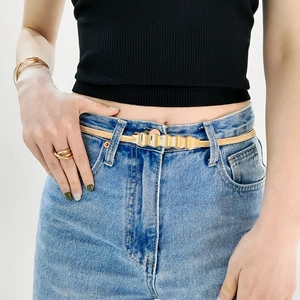 Detail of gold metal spring waist chain with geometric buckle on light blue jeans
