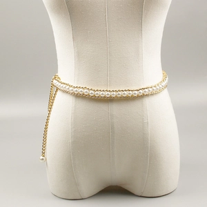 Detail of elegant gold chain belt with white faux pearls on a white mannequin