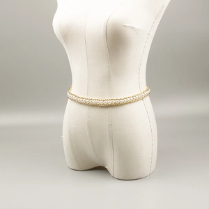 Detail of elegant gold chain waist belt featuring white imitation pearls on a mannequin