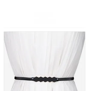 Close-up of black elastic belt with golden hexagonal metal buckle on a white pleated skirt