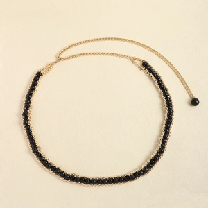 Detail of elegant gold metal chain belt with black round beads and retro charm