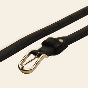 Vue rapprochée d'une ceinture fine en cuir noir avec boucle ardillon dorée polie