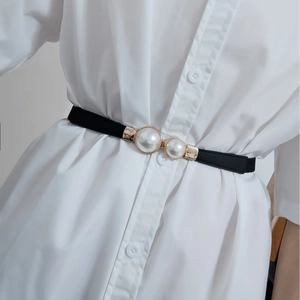 Détail d'une ceinture élastique noire avec boucle en perles sur une robe blanche