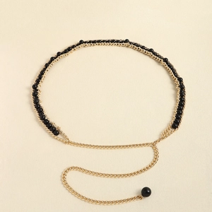 Detail of elegant gold double-layered chain belt featuring black beads and sphere pendant