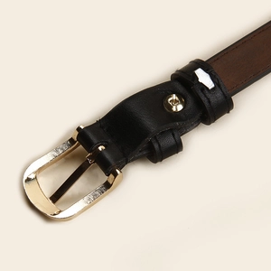 Détail d'une fine ceinture en cuir avec boucle dorée et surpiqûres précises sur le cuir