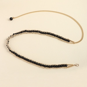 Detail of elegant gold chain belt for women featuring black beads and lobster clasp