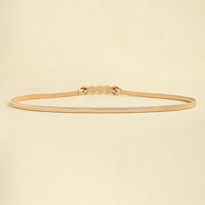 Detail of a gold metallic elastic waist chain with a geometric sawtooth buckle design