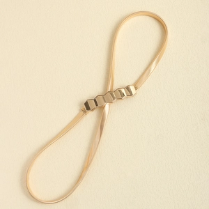 Detail of golden geometric hexagon buckle on a flexible spring metal snake belt