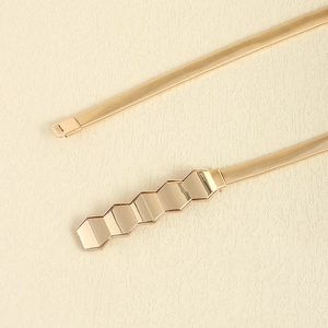 Detailed macro view of the golden hexagonal buckle on a metal spring snake chain belt