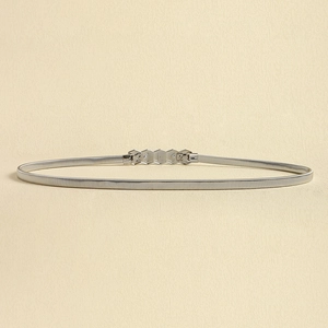 Close-up of a slim silver elastic waist chain with a geometric hexagonal metal buckle
