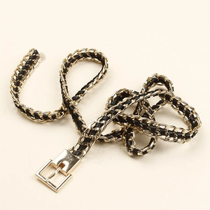 Detailed view of woven golden metal chain and black leather waist belt with gold buckle