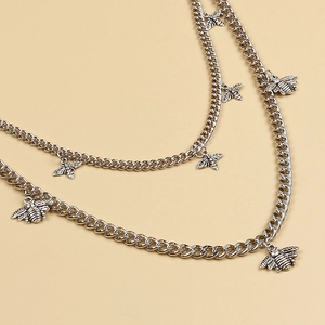 Detail of silver layered waist chain featuring vintage bee charms and flat Cuban links
